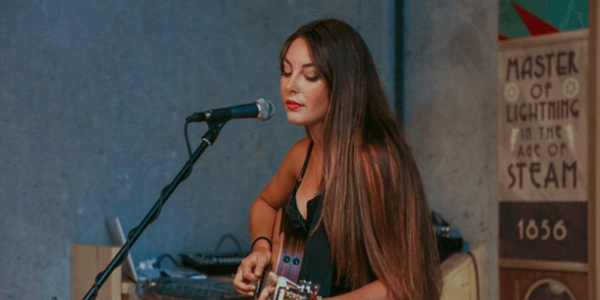 ギターを弾き語りをしている女性の画像